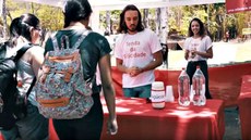 No balcão, representantes do grupo Ideias na Mesa, da UnB, colocavam gás em copos de 300 ml de água, adicionavam corante e dez colheres de açúcar. O resultado ficava muito similar ao de refrigerantes, revelando a quantidade excessiva de açúcar que há nesse tipo de bebida. Imagem: Ideias na Mesa/Consea